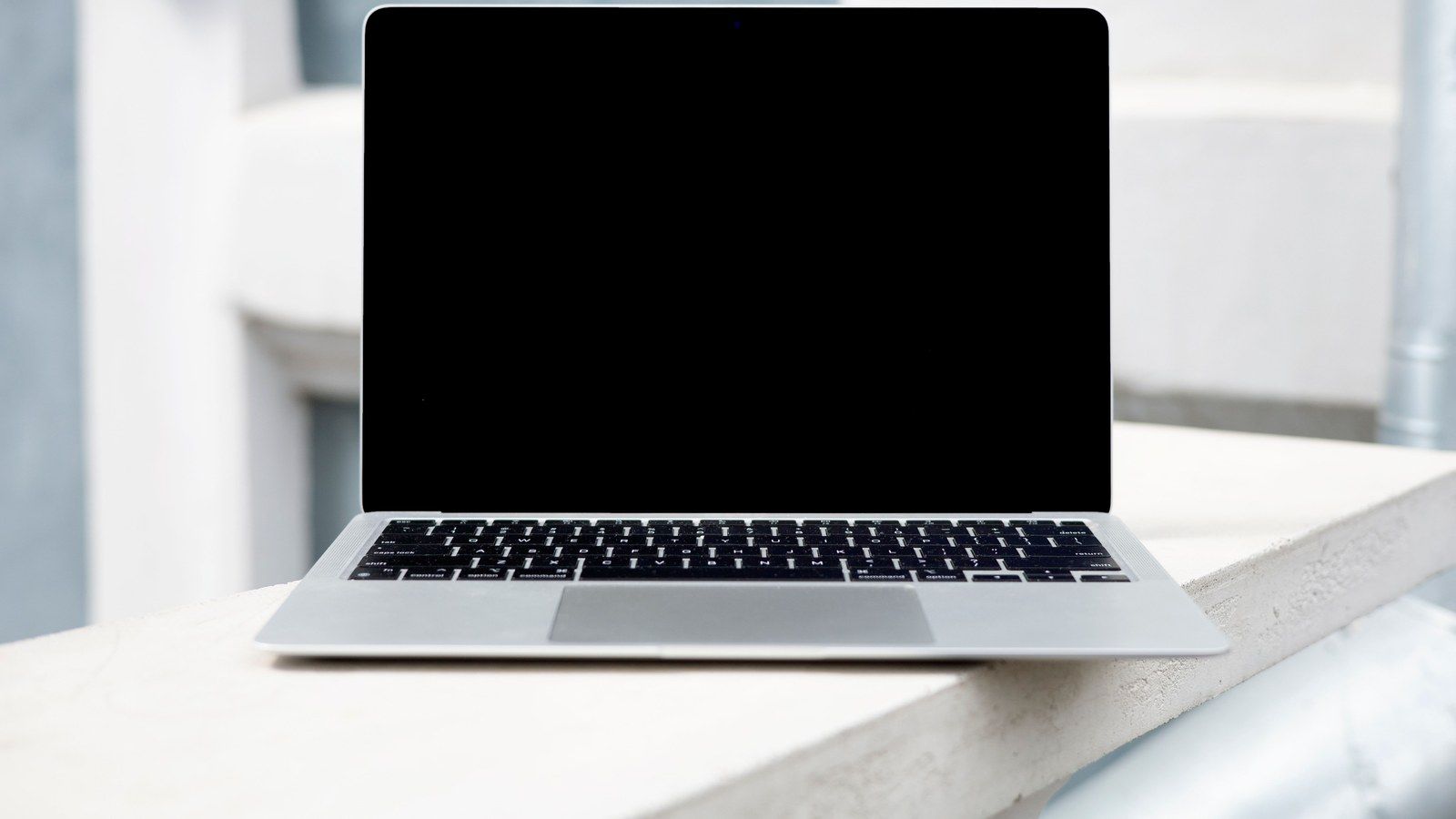 Stock photo of a laptop with a blank screen resting on a stone ledge