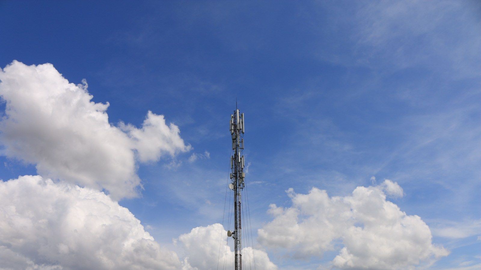 Stock photo of a telecommunications tower against a blue sky, illustrative only