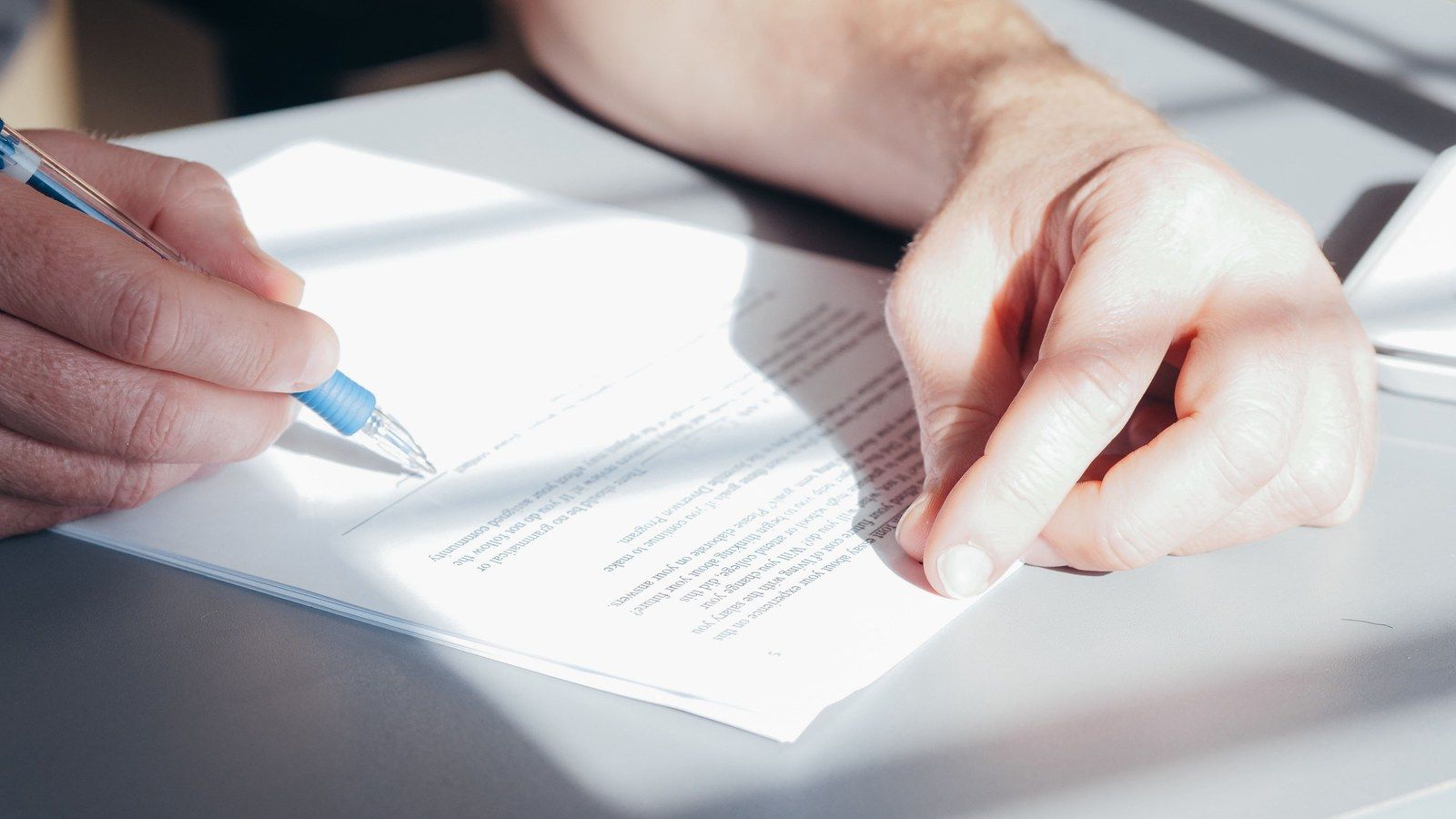 Stock photo of a hand signing a document, illustrative only, not photographed at the actual signing