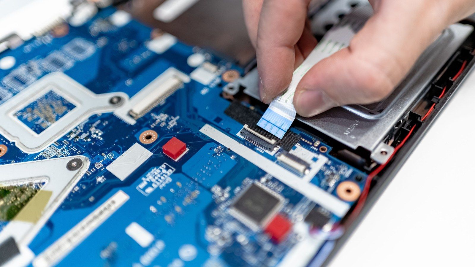 Stock photo of hands repairing a laptop motherboard, illustrative only, not Framework's actual hardware